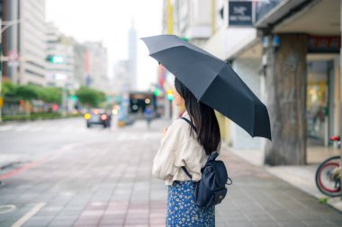 Taipei şehrinde siyah şemsiyeli bir kadın