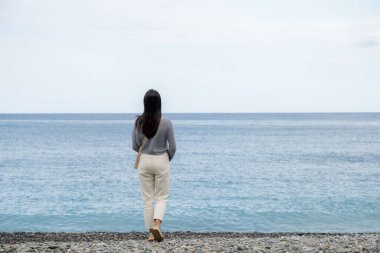 Taş plajda yürüyen bir kadın