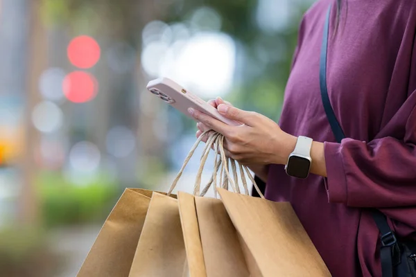 Woman use mobile phone and hold with shopping bag