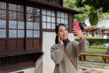 Japon ahşap evinde cep telefonuyla selfie çeken bir kadın. 