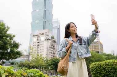 Taipei 'de bir kadın cep telefonuyla selfie çekiyor.