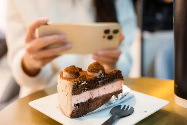 Woman use cellphone to take photo on the cake in restaurant