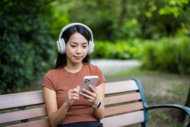 Kadın cep telefonu kullanıyor ve park yerinde oturuyor.