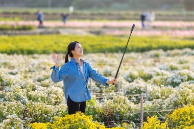 Kadın çiçek çiftliğinin üzerinde fotoğraf çekmek için dijital kamera kullanıyor.