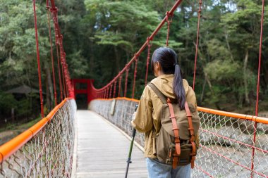 Kadın yürüyüşe çıkıp asma köprü boyunca yürür.