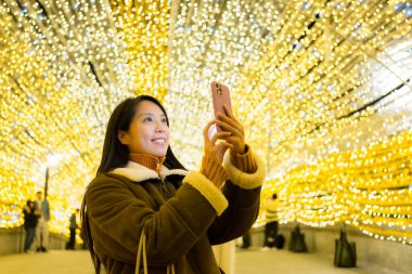 Woman use mobile phone to take photo in Christmas light decoration