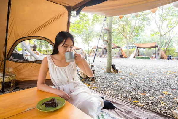 Woman drink of the coffee and sit inside the camping tent