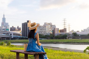Akşamları Taipei 'deki nehir parkının yanında oturan kadın.