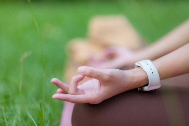 Yoga dersi alan bir kadın açık hava parkında meditasyon yapıyor.