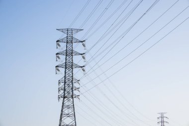 Mavi gökyüzü üzerinde pilon ve yüksek voltaj güç hattı