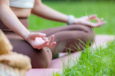 Yoga dersi alan bir kadın açık hava parkında meditasyon yapıyor.