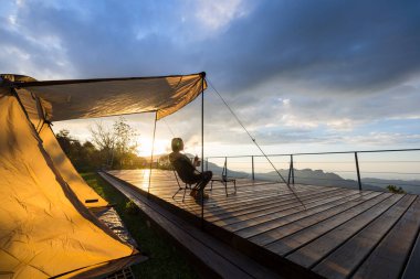 Kadın kampa gider ve günbatımının tadını çıkarır.