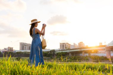 Kadın gün batımında Taipei şehrinde fotoğraf çekmek için dijital kamera kullanıyor.