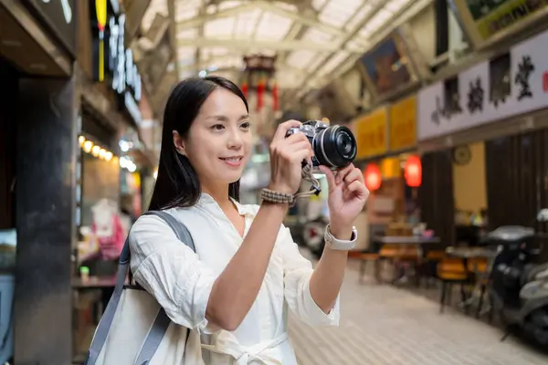 Gezgin kadın, sokak pazarında fotoğraf çekmek için dijital kamera kullanıyor.