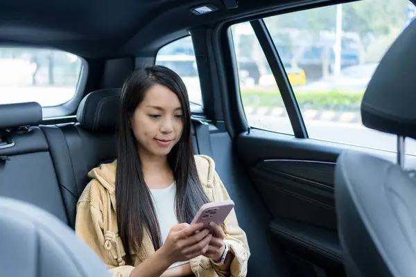 Kadın arabanın içinde cep telefonu kullanıyor.