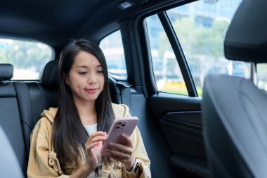 Kadın arabanın içinde cep telefonu kullanıyor.