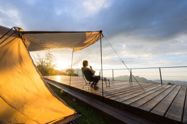 Güzel gün batımı manzaralı bir kadın kampa gider.