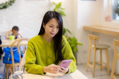 Kadınlar kafede yemek sipariş etmek için cep telefonu kullanırlar.