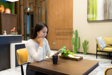 Kadın kahvecide cep telefonu kullanıyor.