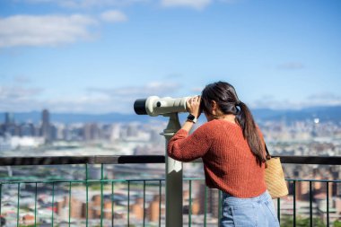 Turist kadın, şehirdeki dürbüne bak.