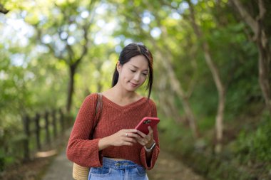 Kadın yeşil bitki arka planında cep telefonu kullanıyor