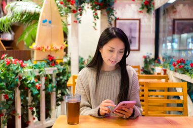 Kadın restoranda cep telefonu kullanıyor. 