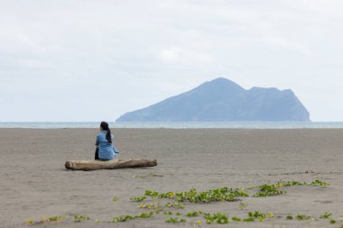Woman sit on the beach and look at the Guishan at Yilan clipart