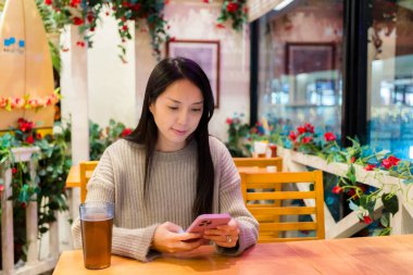 Kadın restoranda cep telefonu kullanıyor.