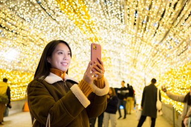 Kadın şehirde fotoğraf çekmek için cep telefonu kullanıyor.