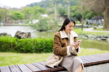 Kadın parkta cep telefonu kullanıyor