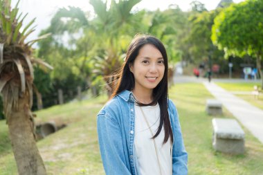 Kadın parkta kameraya gülümsüyor.