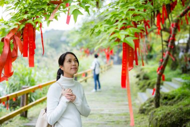 Asyalı kadın bir dilek tut ve kurdeleyi ağaca bağla. 