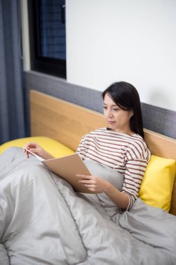 Kadın yatakta defter okudu.