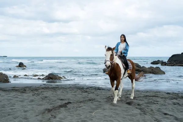 stock image Tourist woman ride a horse beside the sea beach