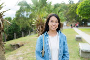 Kadın parkta kameraya gülümsüyor.