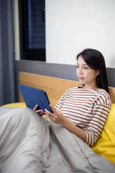 女性はベッドでタブレットコンピュータで読む ストック画像