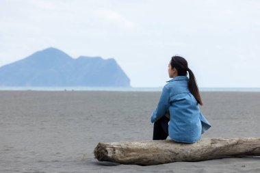 Woman sit on the beach and look at the Guishan at Yilan clipart