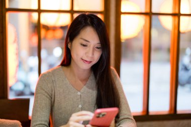 Kadın restoranda cep telefonu kullanıyor.