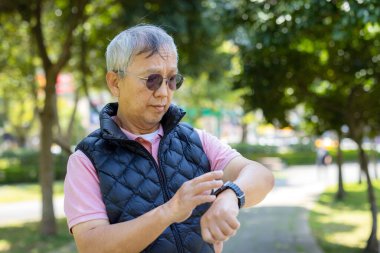 Son sınıf öğrencisi parkta akıllı saat kullanıyor.