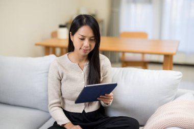 Evdeki tablet bilgisayarda okuyan kadın