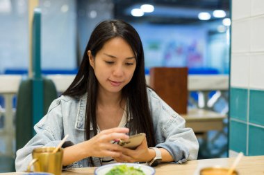 Kadın kafede cep telefonu kullanıyor