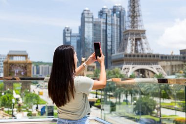 Turist kadın Macau 'da fotoğraf çekmek için cep telefonu kullanıyor.