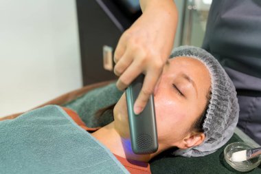 Kadın güzellik salonunda yüz bakımı uygular.