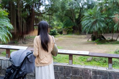 Bebek arabasıyla Asyalı anne hayvanat bahçesi parkını ziyaret ediyor.