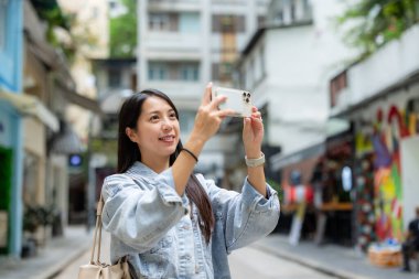 Turist kadın fotoğraf çekmek için cep telefonu kullanıyor.