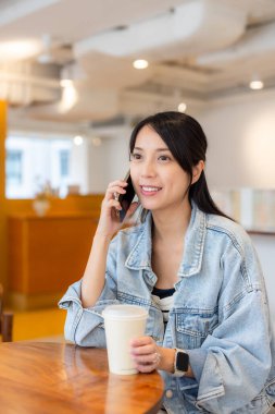 Kahve dükkanında kadınlar akıllı telefonlarla konuşur.