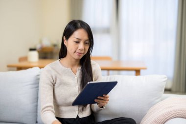 Evdeki tablet bilgisayarda okuyan kadın