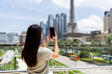 Turist kadın Macau 'da fotoğraf çekmek için cep telefonu kullanıyor.