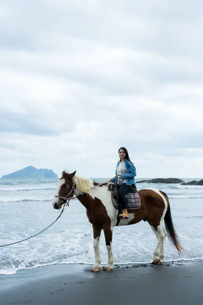 stock image Tourist woman ride a horse beside the sea beach