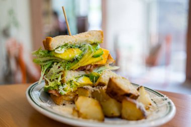 Kahve dükkanında avokado ve ızgara patatesli sandviç.